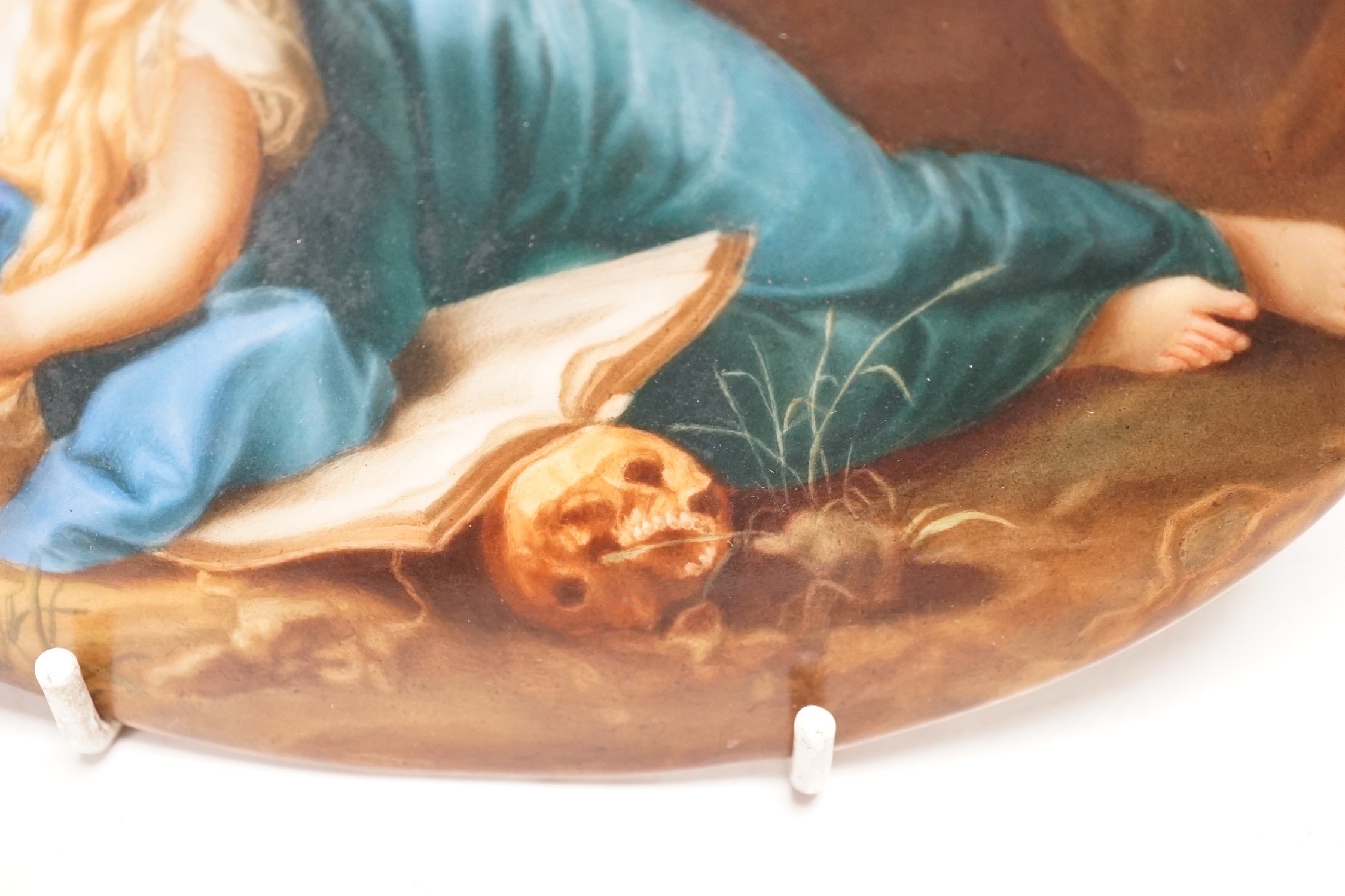 A 19th century painted porcelain oval plaque of a reclining lady reading a book. The reverse stamped L. Sturm Dresden. 15x19.5cm